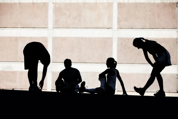 Men and women runners stretching. — Stock Photo, Image