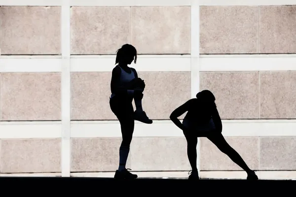 Two women stretching before running. — Stock Photo, Image