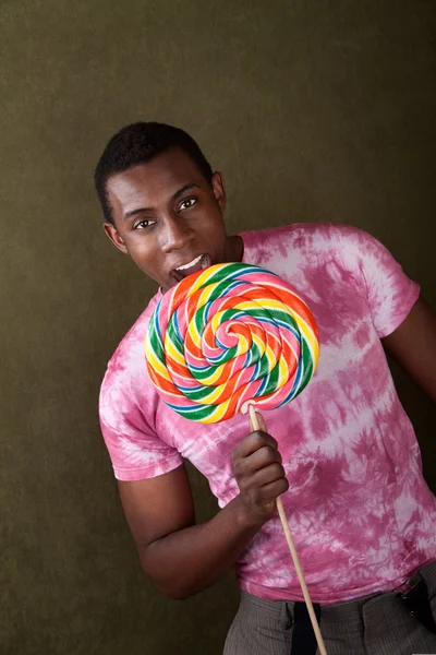 Young Man Bites Into a Giant Lollipop — Stock Photo, Image