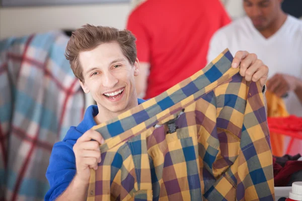 Człowiek uśmiechając gospodarstwo koszula — Zdjęcie stockowe
