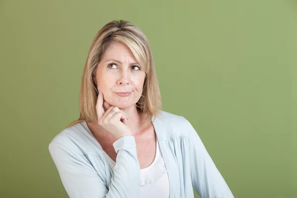 Vrouw met vinger op kin — Stockfoto