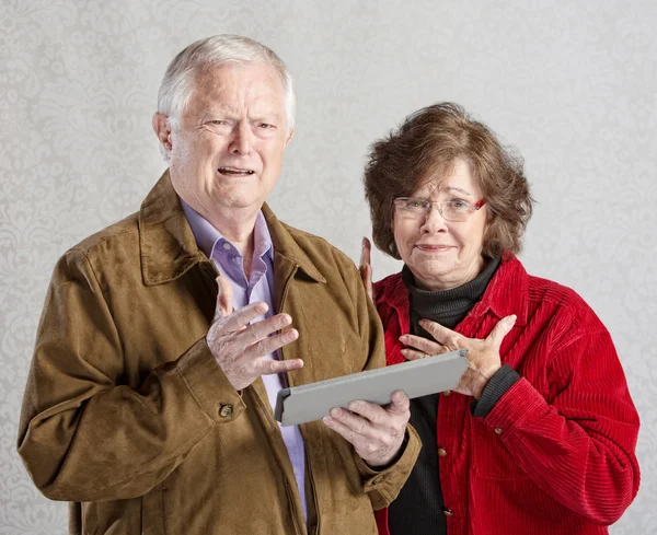 Förbryllad par hålla Tablet — Stockfoto