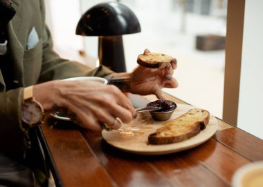 Kafede kahvaltı yapan bir kadın, kızarmış ekmek ve reçel.