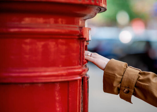 hand  of woman sending letter in a red box
