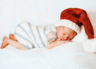 Noel Baba şapkalı bebek yatakta uyuyor.