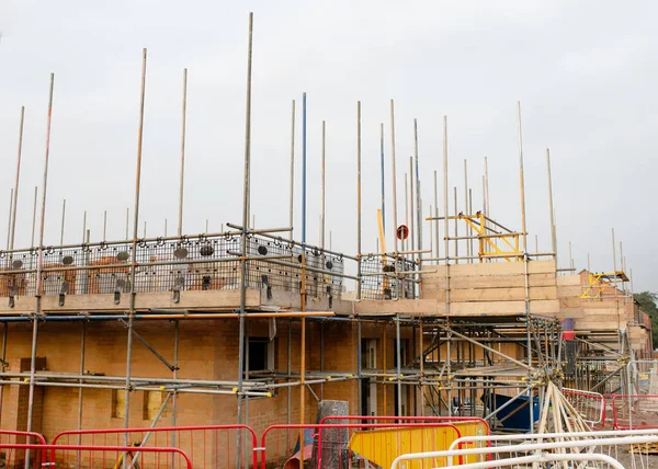 stock image New house with brick wall is being erected and scaffold system placed around it to allow bricklayer to work at next level