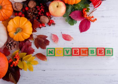 autumn wooden background with leaves, pumpkins  with text November