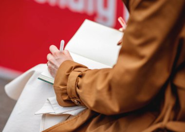 left - handed person writing on a notebook  in a cafe