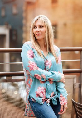 blondie woman in a green shirt and jeans  waiting somebody in city