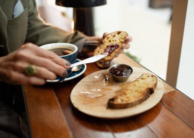 person eating breakfast toast and jam and drinking coffee in the cafe