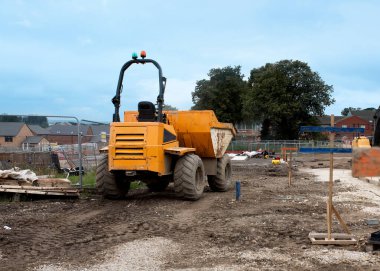 Dumper parked next to profiles set by site engineer for levels for new access road construction on new residential housing development construction site