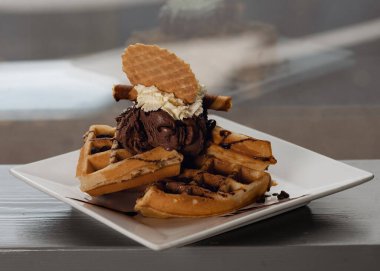 Belçika Waffle 'ı dondurmalı ve çikolatalı beyaz tabakta bir kafede.