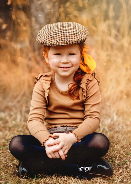 Smiling Red Haired Girl Classic Cap Sitting Autumn Park — стоковое фото