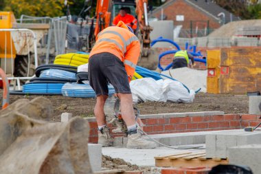 Bricklayer cutting concrete blocks using petrol disc cutter while working on new residential housing development construction site
