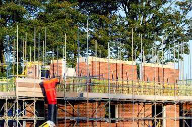 New residential house under construction and scaffolds erected around it to provide safe working platform to brickl and other construction workers