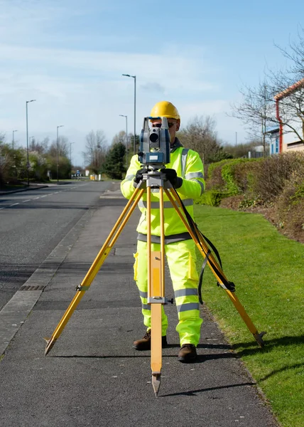 Site engineer installing robotic total station on top of wooden tripod above control point to perform surveying and setting out