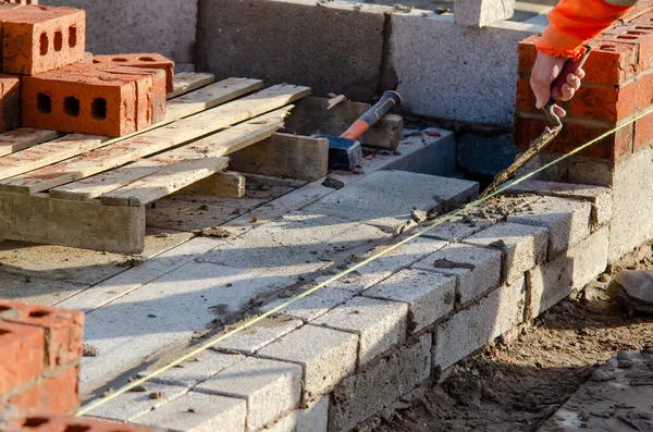 Bricklayer laying bricks and blocks on mortar on new residential house construction