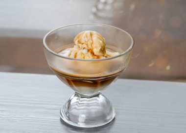 Kafe masasında kahve soslu vanilyalı dondurma.