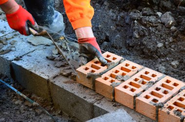 Turuncu hi-viz 'deki tuğla ustası inşaat alanına tuğla döşüyordu