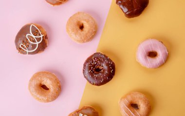 Pembe ve sarı arka planda çeşitli donutlardan oluşan bir koleksiyon.