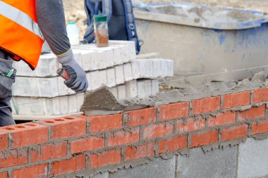 Yeni konut inşaatına harç tuğlası döşeyen tuğla ustası.