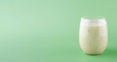 Yeşil arka planda büyük yeşil yapraklı bir bardakta vejetaryen yeşil içeceği.