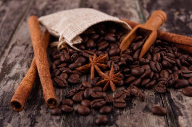 Çikolata, tarçın çubukları ve ahşap arka planda kahve çekirdekleri.
