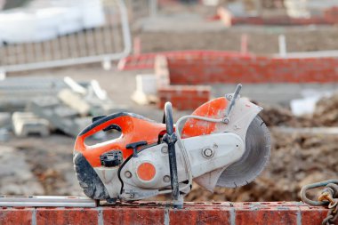 İnşaat alanındaki tuğla duvarın tepesindeki beton testere.