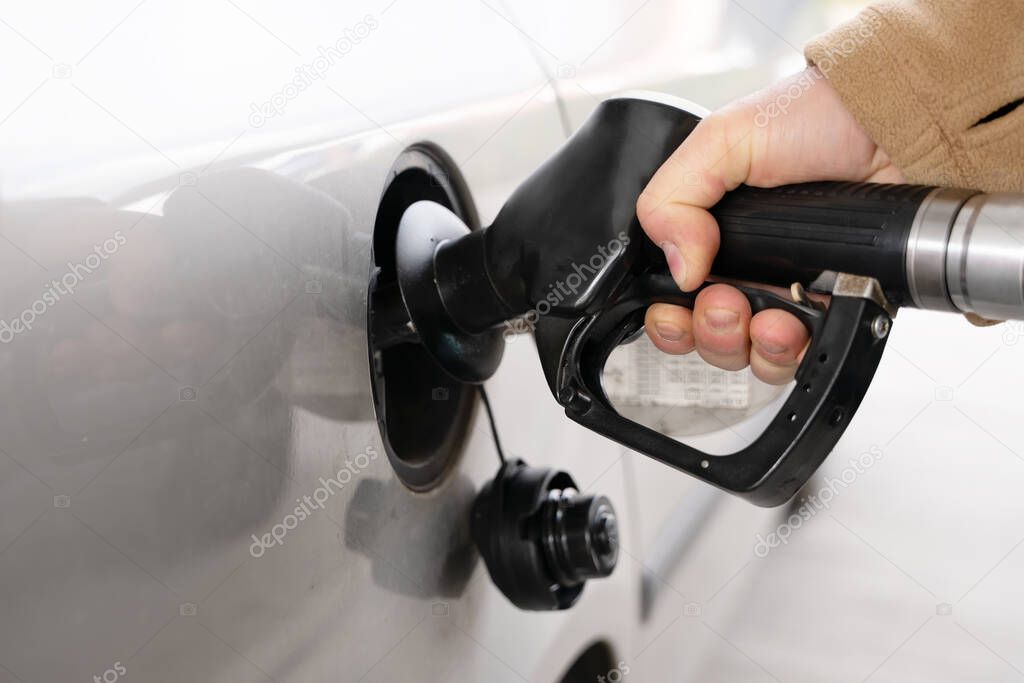 A man filling fuel tank of his car with diesel fuel at the petrol station close up, as cost of fuel going up