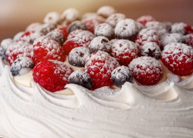 Yeşil zemin üzerinde yaban mersini ve ahududu olan kremalı pasta.