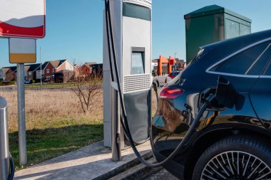 Elektrikli araç şarj istasyonu ve şarj etmeye bağlı bir araba. Şarj etme zamanı.