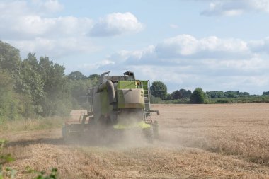 Modern bir biçerdöver tarafından yaz mevsiminde buğday hasadı. Çiftçiler yiyecek tedarik ediyor ve ulusu besliyor.