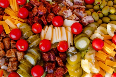 Kiraz domatesleri, tatlı biber, salatalık turşusu, sarımsak turşusu, zeytin, sosis, farklı peynir, ahşap tabakta pastırma. Atıştırmalık