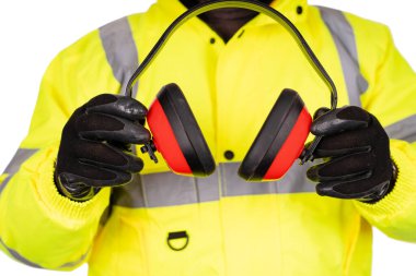 A construction worker in  yellow hi-viz coat on white background gives foam-filled padded ear defenders to the viewer. Wear hearing protection in a noisy environment to protect your hearing safety poster concept
