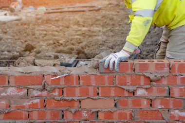 Yeni konut inşaatına tuğla döşeyen tuğla ustası.
