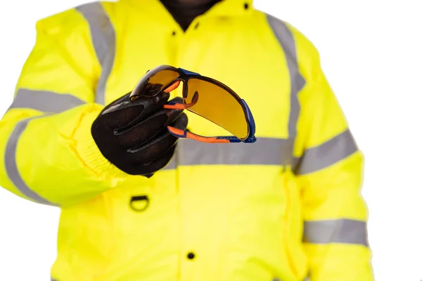 一名穿着白色背景的黄色透明外套的建筑工人给观众们提供了深色的安全玻璃 佩戴安全眼镜保护眼睛安全海报的概念 — 图库照片