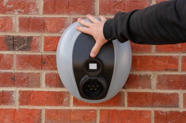 Kırmızı tuğla duvara monte edilmiş özel elektrikli araç şarj istasyonu.