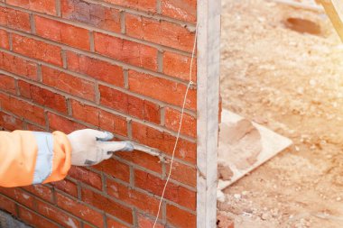 Yeni konut inşaatına tuğla döşeyen tuğla ustası.