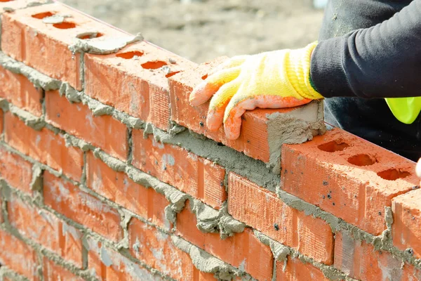 Yeni konut inşaatına tuğla döşeyen tuğla ustası.