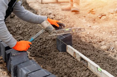 Yarı beton karışımına yol ve yaya yolu inşaatı sırasında kaldırım blokları kuran inşaatçı