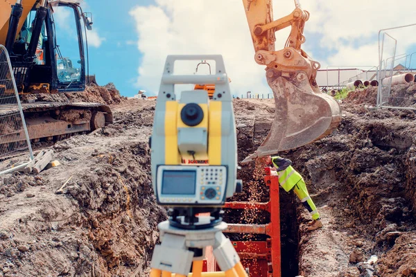 Deep drainage excavation works, with red trench support box installed into the trench and yellow total station next to it