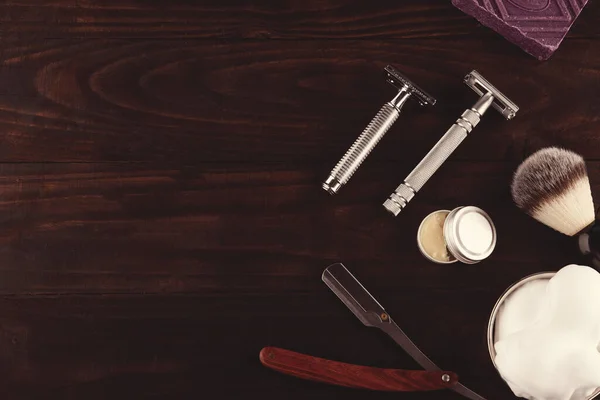 vintage razors, shaving brush, soap and foam in a bowl on a  dark wooden background. View above. Space for text