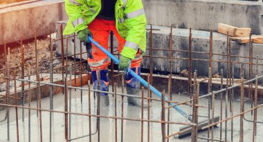 Çukur tabanına ıslak hazır beton döküp düzleştiriyor.