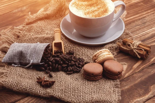 Tasse Kaffee Bohnen Zimt Makronen Und Anis Auf Dem Holzuntergrund — Stockfoto