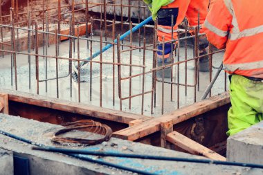 Çukur tabanına ıslak hazır beton döküp düzleştiriyor.