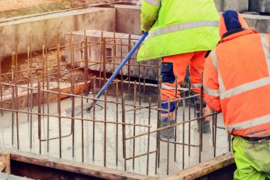 Çukur tabanına ıslak hazır beton döküp düzleştiriyor.