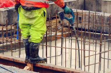 Çukur tabanına ıslak hazır beton döküp düzleştiriyor.