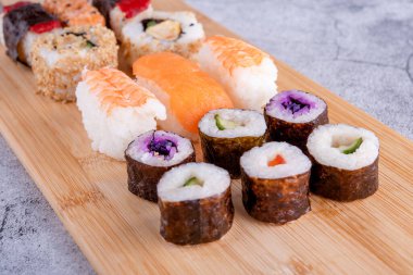 sushi set  with chopsticks and soy on a wooden plate ready to eat on grey background