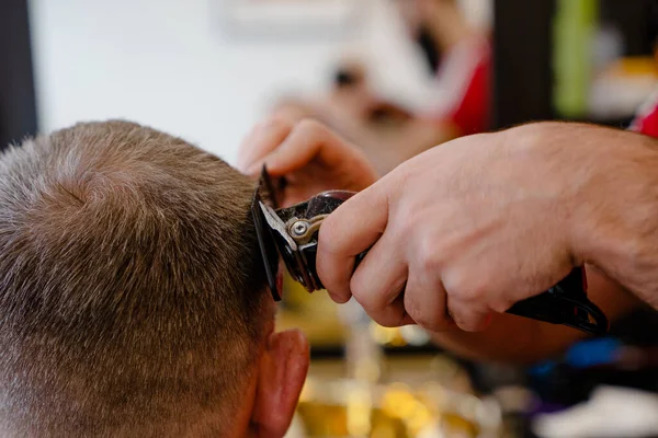 An old man enjoing haircut by a master in a barbershop. An old man gets a stylish haircut