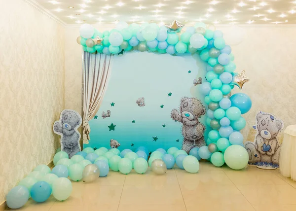 Photo zone in bright room decorated with colorful balloons and bears